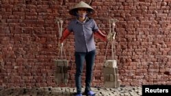 Phung Thi Hai, 54, carries bricks at a factory outside Hanoi, Vietnam, Feb. 27, 2017. 