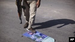 A rebel fighter steps over a calendar with Moammar Gadhafi's picture at a checkpoint in Tripoli, Libya, July 30, 2011