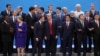 President Donald Trump, front center, listens to France's President Emmanuel Macron as they pose with world leaders for a group picture at the start of the G20 Leader's Summit inside the Costa Salguero Center in Buenos Aires, Argentina, Friday, Nov. 30, 2018.
