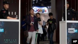 Attendees walk past security guards as they pass by the Google booth at the Global Mobile Internet Conference in Beijing, China, April 29, 2016.