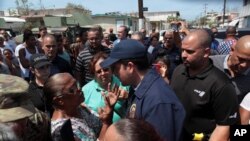 Puerto Rico's Governor Ricardo Rossello (center) talks to a woman during a distribution of relief items, after the area was hit by Hurricane Maria in San Juan, Puerto Rico Sept. 24, 2017.