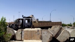 File - Military truck damaged in clashes between Islamic State fighters and Iraqi security forces at a military base north of Baghdad.