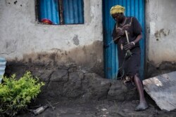 A woman inspects the small dam she built in front of the door to her home, which nonetheless did not withstand flooding, in Dijeri village, on the outskirts of Juba, South Sudan, Oct. 1, 2021.