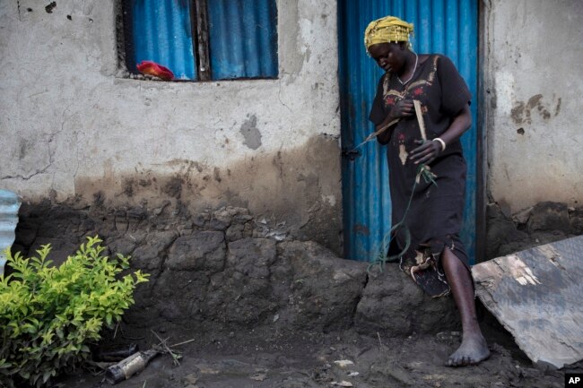 A woman inspects the small dam she built in front of the door to her home, which nonetheless did not withstand flooding, in Dijeri village, on the outskirts of Juba, South Sudan, Oct. 1, 2021.
