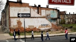 A group of boys walk past a partially collapsed row house in Baltimore, Maryland, Apr. 4, 2013. The U.S. Census Bureau estimates that 20 percent of American children are impoverished.