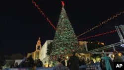Người Palestine tập trung quanh cây Giáng sinh tại Quảng trường Manger, bên ngoài Nhà thờ giáng sinh ở thị trấn Bờ Tây Bethlehem. 