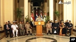 Lt. Gen. Abdel-Fattah el-Sissi, center, flanked by military and civilian leaders addresses the nation on Egyptian state television, July 3, 2013. 