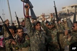 Iraqi army soldiers celebrate on the outskirts of Qayyarah, Iraq, Oct. 19, 2016. When troops arrived at a nearby village, they found the residents had risen up and killed Islamic State fighters.