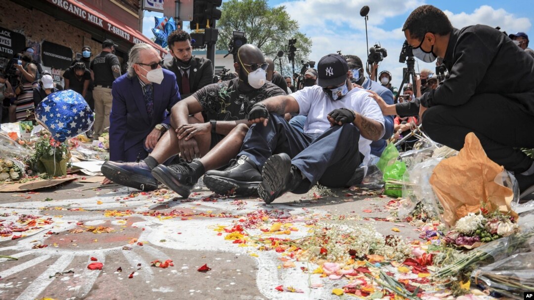 FILE - in this June 1, 2020 file photo, an emotional Terrence Floyd, second from right, is comforted as he sits at the spot at the intersection of 38th Street and Chicago Avenue, Minneapolis, Minn., where his brother George Floyd, encountered police.