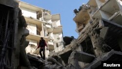 A man stands on a destroyed building after what activists said was an air raid by forces loyal to Syrian President Bashar Al-Assad, in Aleppo's district of Al Sukari Dec. 24, 2013.