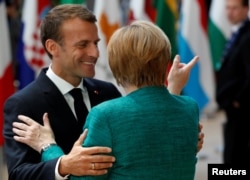 German Chancellor Angela Merkel and French President Emmanuel Macron greet each other as they arrive at an European Union leaders summit in Brussels, June 28, 2018.