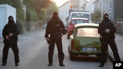 FILE - Special police officers secure a street near the house where a Syrian man lived before the explosion in Ansbach, southern Germany, July 25, 2016.