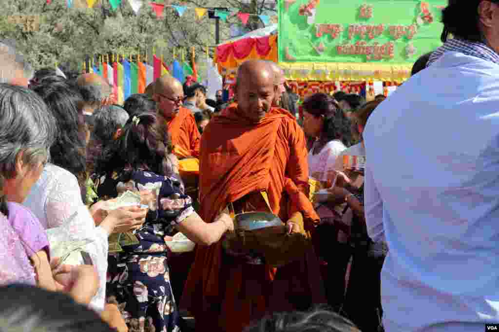 អ្នកកាន់ពុទ្ធសាសនាប្រគេនម្ហូបអាហារនិងប្រាក់កាសដល់ព្រះសង្ឃ។ (ចាប ចិត្រា/VOA)