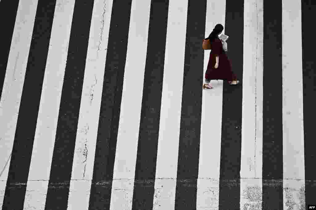 A woman crosses a street in Tokyo&#39;s Shinbashi area.
