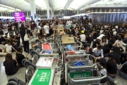 FILE - Protesters use luggage trolleys to block the walkway to the departure gates during a demonstration at the Airport in Hong Kong, Aug. 13, 2019.