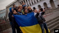 FILE - People holding a Ukrainian flag pose for a photo in Kyiv's Independence Square.