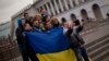 FILE - People holding a Ukrainian flag pose for a photo in Kyiv's Independence Square.