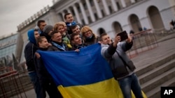 FILE - People holding a Ukrainian flag pose for a photo in Kyiv's Independence Square.