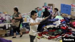 A migrant child chooses clothing at the Sacred Heart Catholic Church temporary migrant shelter in McAllen, Texas, June 27, 2014. 