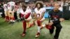 Colin Kaepernick (numéro 7) et Eli Harold (58) des San Francisco 49ers s'agenouillent lors de l'hymne national avant le match contre les Falcons à Atlanta le 18 décembre 2016.