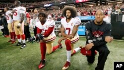 FILE - San Francisco 49ers quarterback Colin Kaepernick (7) and outside linebacker Eli Harold (58) kneel during the playing of the national anthem before an NFL football game against the Atlanta Falcons in Atlanta. 