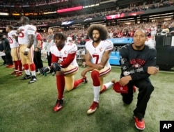 FILE - San Francisco 49ers quarterback Colin Kaepernick (7) and outside linebacker Eli Harold (58) kneel during the playing of the national anthem before an NFL football game against the Atlanta Falcons in Atlanta.