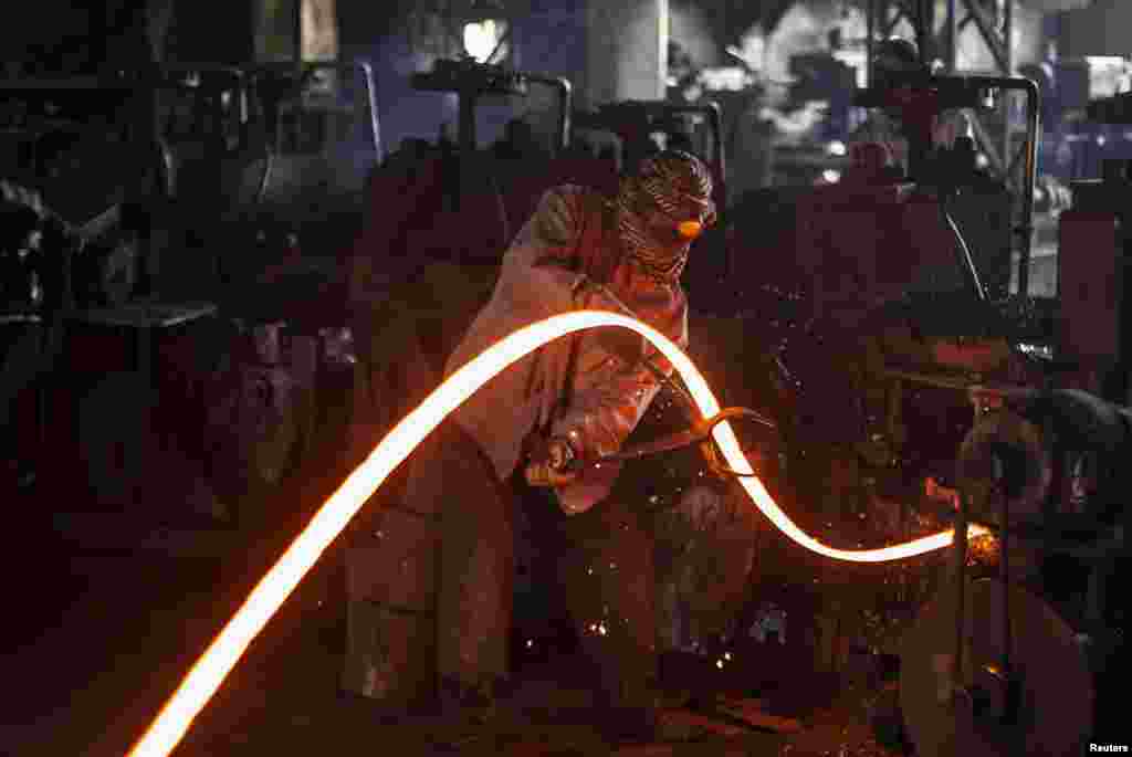 A worker manipulates a hot iron rod at a factory in Islamabad, Pakistan.