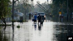 Warga melintasi jalanan yang tergenang banjir pasca badai Ida melanda Lafitte, Louisiana. 