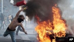 A protestor hurls a canister during clashes in Rome, Saturday, Oct. 15, 2011. Protesters smashed the windows of shops in Rome and torched a car as violence broke out during a demonstration in the Italian capital.