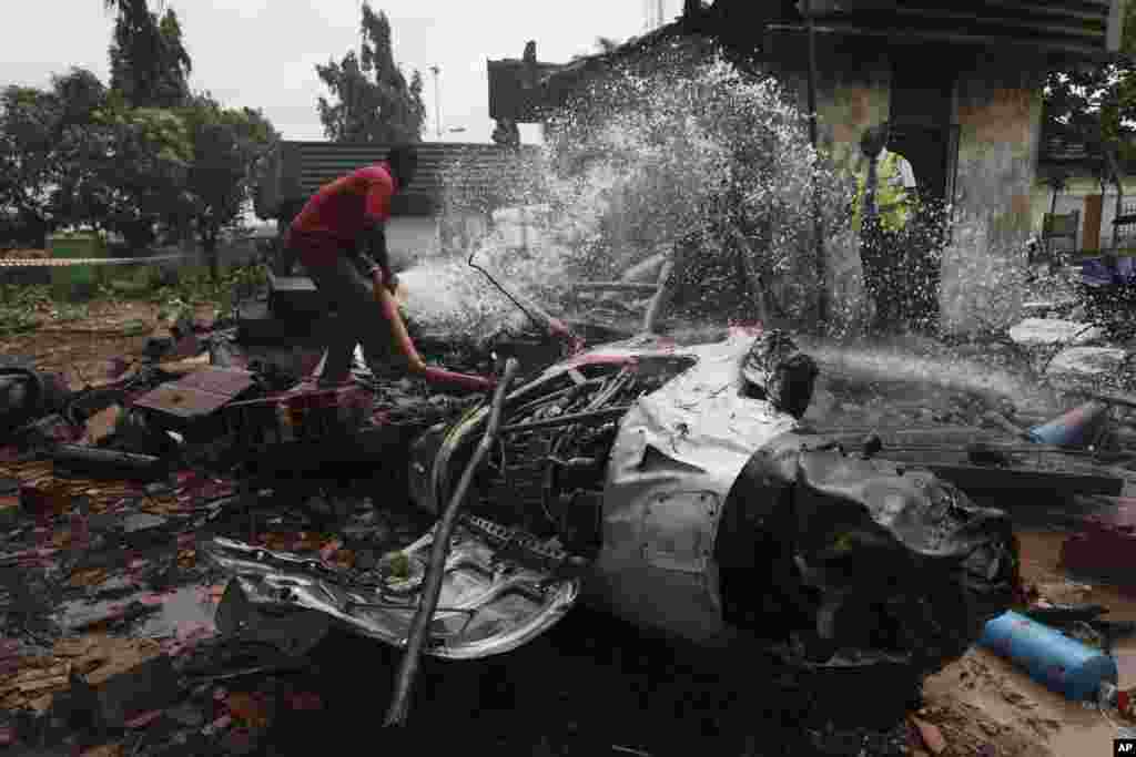 A rescue worker douses a part of the wreckage of a charter passenger jet that crashed soon after take off from Lagos airport, Nigeria, Oct. 3, 2013.