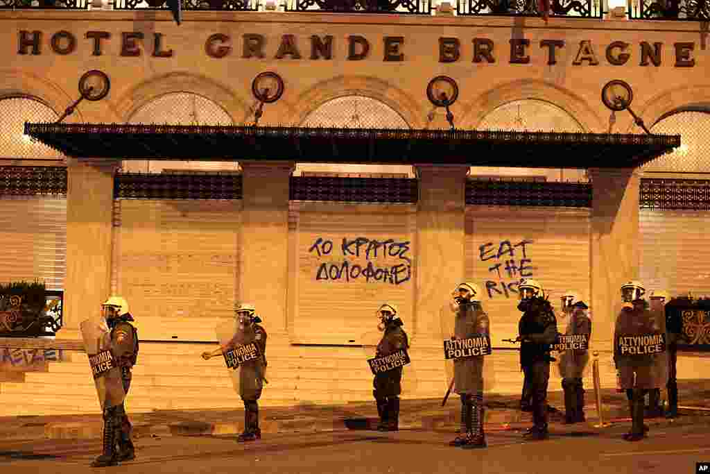Riot police secure the area outside a shuttered luxury hotel where graffiti reads ''the state murders.'' (AP)