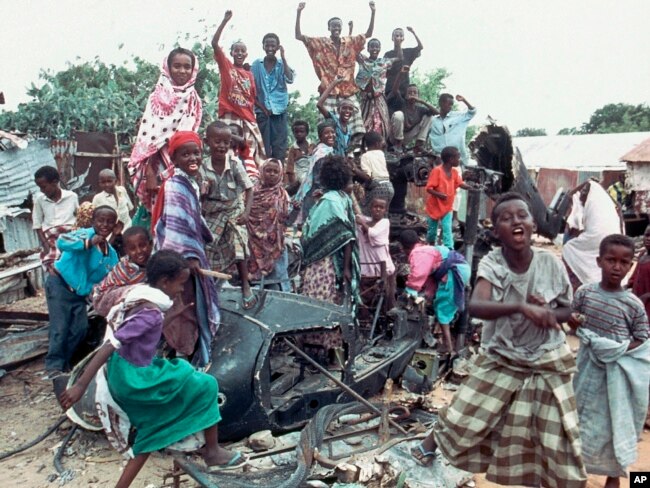 FILE - In this Oct. 19, 1993 photo, a group of young Somalis chant anti-American slogans while sitting atop the burned out hulk of a U.S. Black Hawk helicopter, shot down during a firefight with Somali guerrillas, in Mogadishu, Somalia.