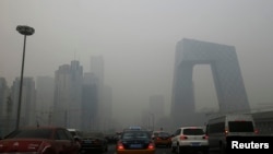 Cars travel on a road amid heavy haze in Beijing, Feb. 21, 2014. 