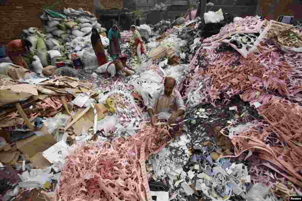 Seorang pria memisahkan kardus dan rexine untuk didaur ulang, yang akan digunakan untuk bagian dalam sepatu kulit, di kota Lahore, Pakistan.