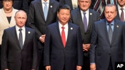 Chinese President Xi Jinping (center) stands with Russian President Vladimir Putin (left) Turkish President Recep Tayyip Erdogan (right) and other leaders to pose for a group photo before the opening ceremony of the Belt and Road Forum the China National Convention Center in Beijing, May 14, 2017.