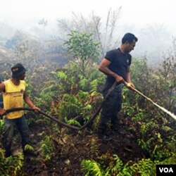 Petugas memadamkan kebaran hutan di Bengkalis, Riau (Oktober 2010). Indonesia sepakat menghentikan pembakaran hutan dan mengurangi emisi rumah kaca.