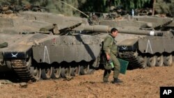 FILE - An Israeli soldier walks past tanks near the Israel and Gaza border, July 10, 2014. 
