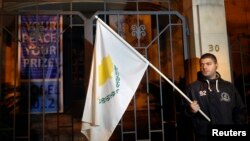 An anti-Troika protester holds a Cypriot flag during a demonstration outside the EU offices in Nicosia Mar. 24, 2013.