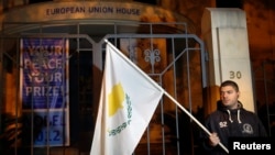3月24日一名塞浦路斯抗议者在尼科西亚的欧盟办公室外手持塞浦路斯国旗示威