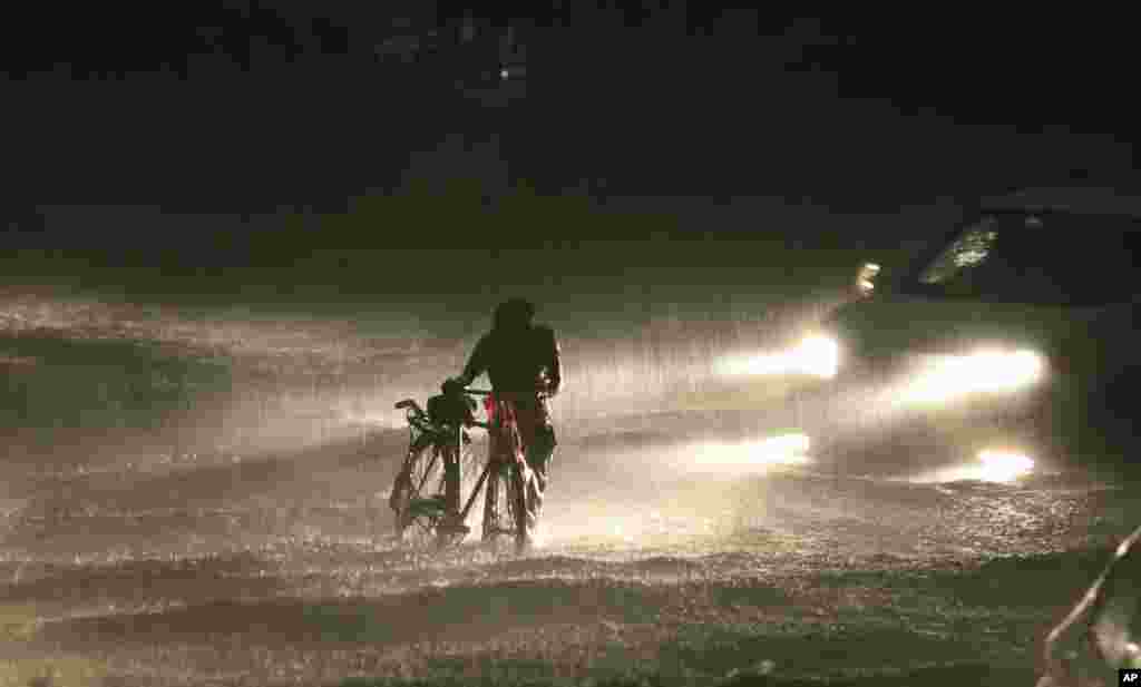 인도 잠무에서 한 남성이 자전거를 끌고 폭우 속을 걷고 있다.