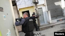 Polisi membidik senjata mereka saat operasi penggerebekan jaringan narkoba di kawasan kumuh, Jacarezinho, di Rio de Janeiro, Brazil, Kamis, 6 Mei 2021. 