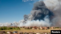 Gumpalan besar asap dari kebakaran di Black Forest membumbung ke angkasa, mengancam rumah-rumah di sebelah utara timur Colorado Springs, Colorado (11/6). Sedikitnya 90 rumah dilaporkan musnah terbakar, dan 7.000 warga terpaksa meninggalkan rumah mereka dalam musibah ini.