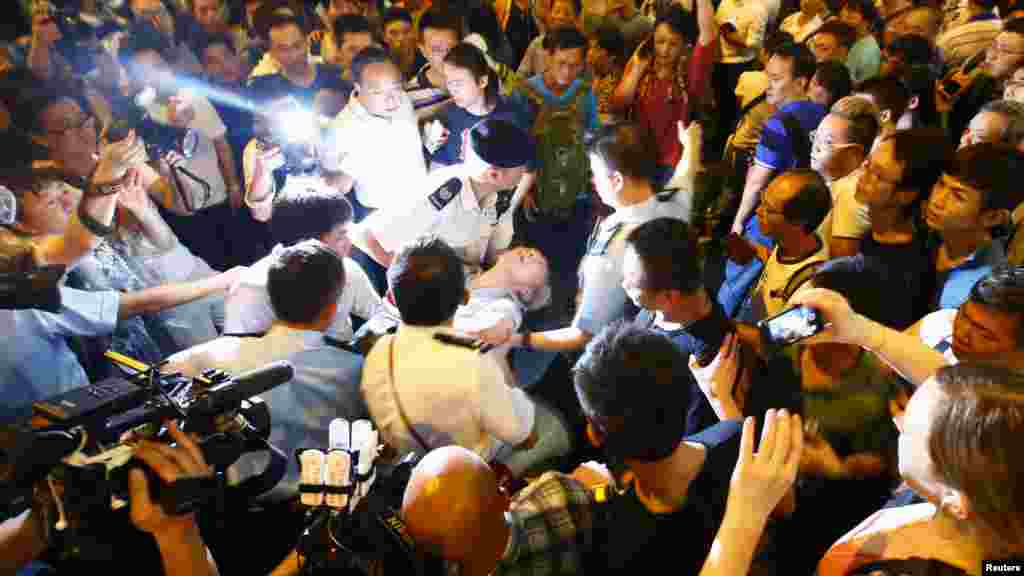 Police remove a man who collapsed during confrontations between anti-Occupy Central protesters and pro-democracy protesters on a main street at Hong Kong's Mongkok shopping district, Oct. 3, 2014. 