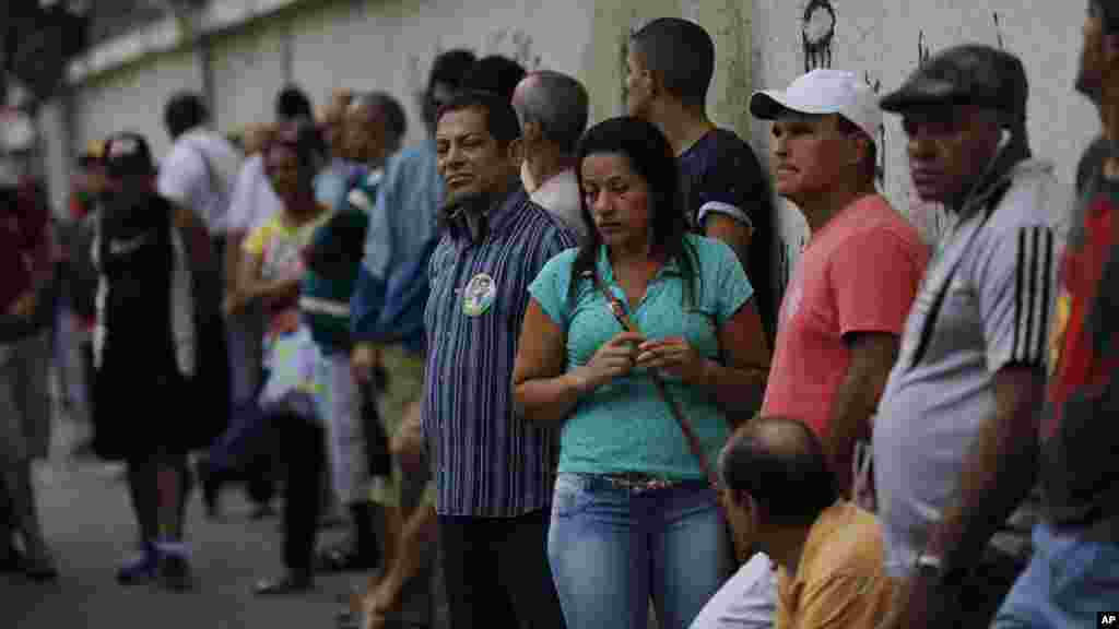 People wait in line to vote in general elections outside a school at the Mare Complex slum in Rio de Janeiro, Brazil, Oct. 26, 2014. 