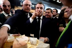 French President Emmanuel Macron samples cheese during a visit to the 57th International Agriculture Fair (Salon international de l'Agriculture) at the Porte de Versailles exhibition center in Paris, France Feb. 22, 2020.