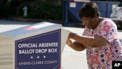 FILE - In this Oct. 19, 2020 file photo, a voter drops their ballot off during early voting in Athens, Ga. 