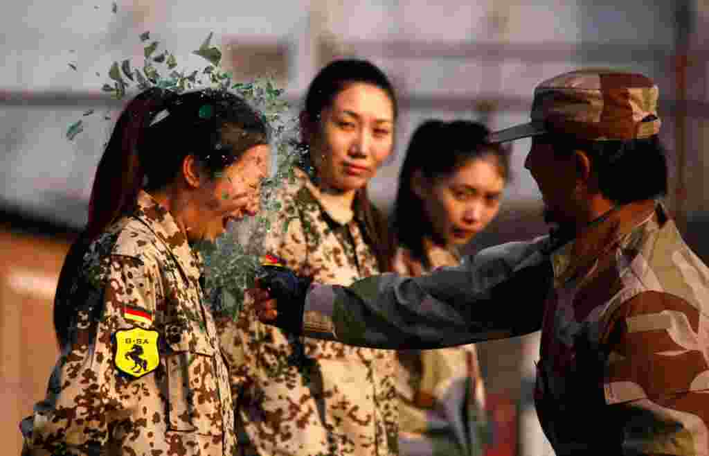 Un instructor de la guardia especial china, rompe una botella en la cabeza de una recluta durante una sesión de entrenamiento de las primeras mujeres guardaespaldas en Beijing, China, 13 de enero de 2012.