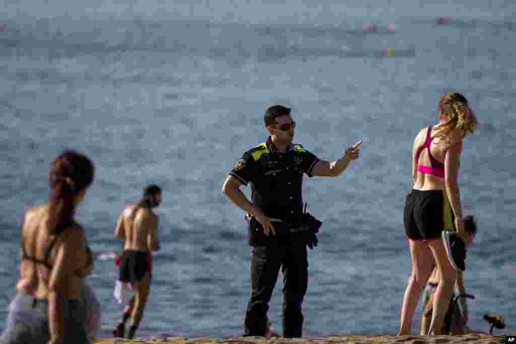 در شهر بارسلون، پلیس به مردم در ساحل درباره رعایت &laquo;فاصله&zwnj;گذاری اجتماعی&raquo; هشدار می&zwnj;دهد. اسپانیا شاهد مرگ ۲۷ هزار نفر بر اثر کرونا بود و تازه سواحل را بازگشایی کرده است.&nbsp;