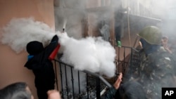 A pro-Russian protester fires a fire extinguisher at riot police inside at a police station building in Odessa, Ukraine, Sunday, May 4, 2014. Several prisoners that were detained during clashes that erupted Friday between pro-Russians and government suppo