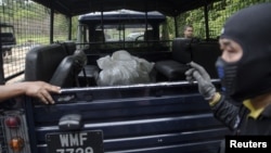 Thành viên trong toán pháp y đưa các túi đựng hài cốt các nạn nhân buôn người lên xe từ các ngôi mộ trong rừng rậm gần biên giới Thái Lan-Malaysia, ngày 27/5/2015.